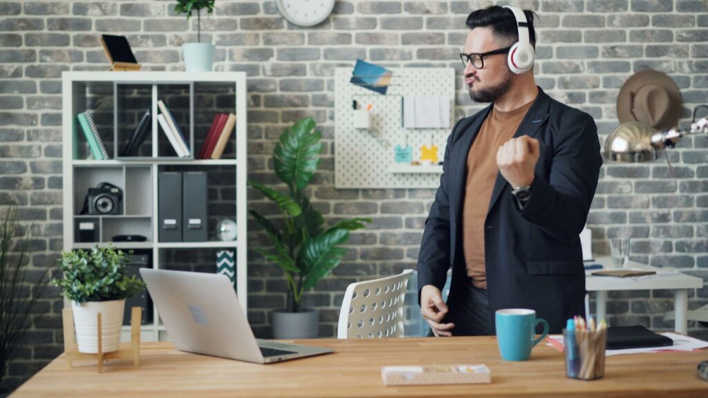 a man wearing headphones standing in front of a laptop